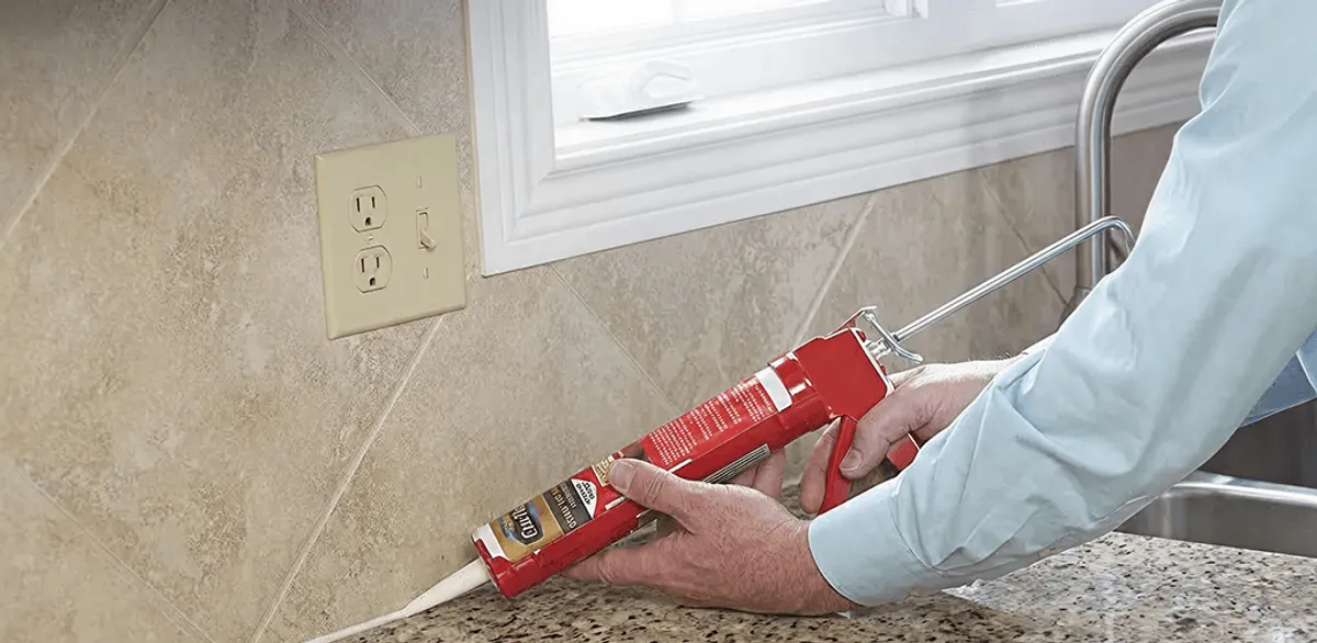 Handyman applying caulk along a kitchen backsplash and countertop seam in Reno, NV